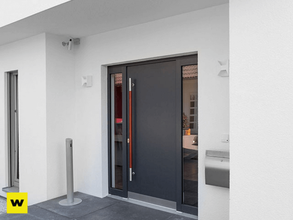 Moderne Haustür aus Aluminium mit Seitenteil und Briefkasten an weißer Hausfassade.